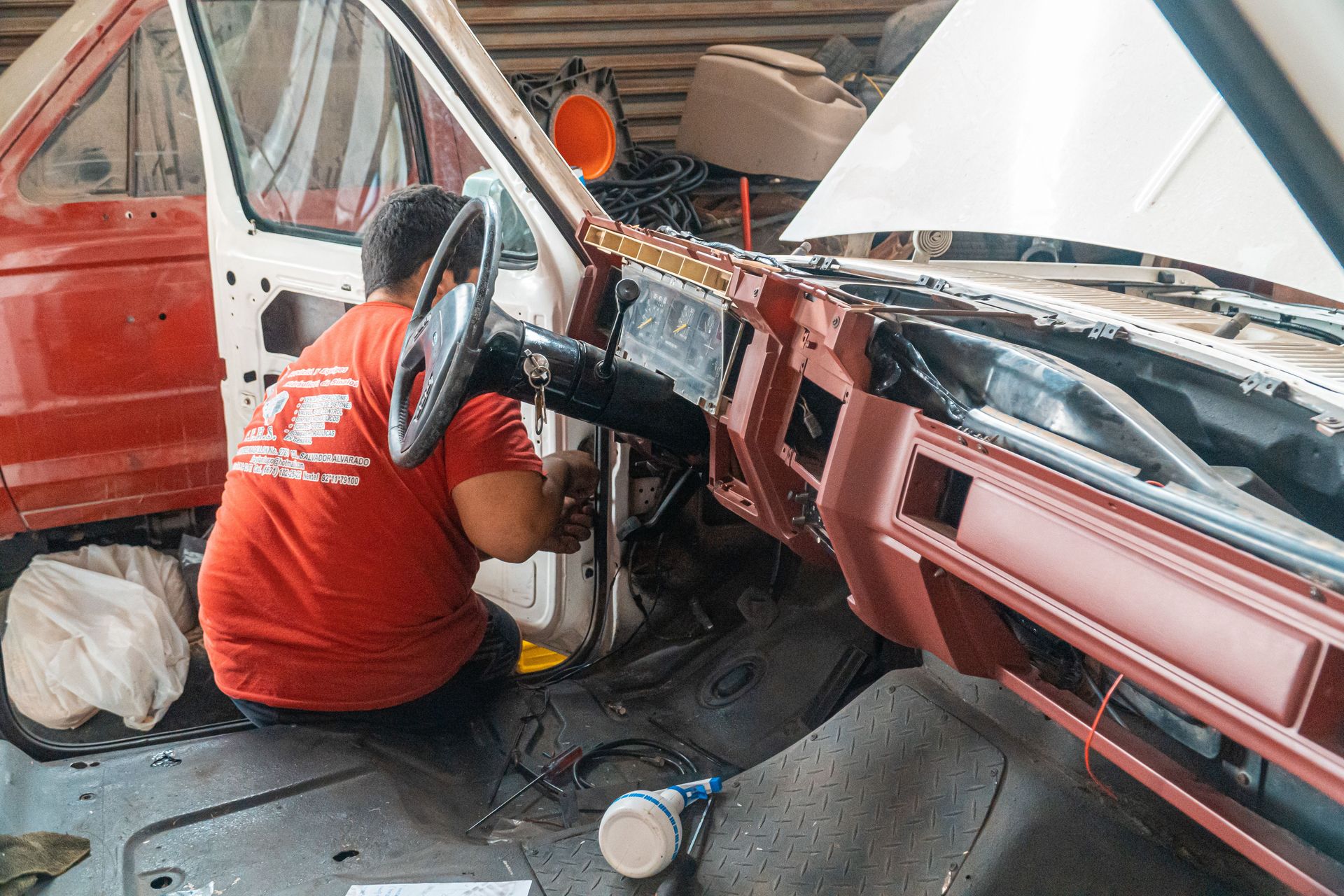Mechanic working on a car dashboard interior in a repair shop, focusing on vehicle restoration.