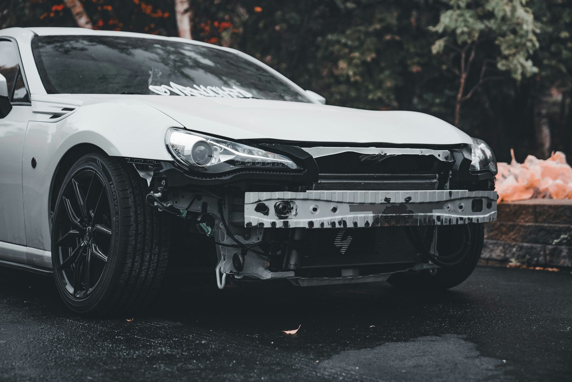 White car with bumper removed outdoors